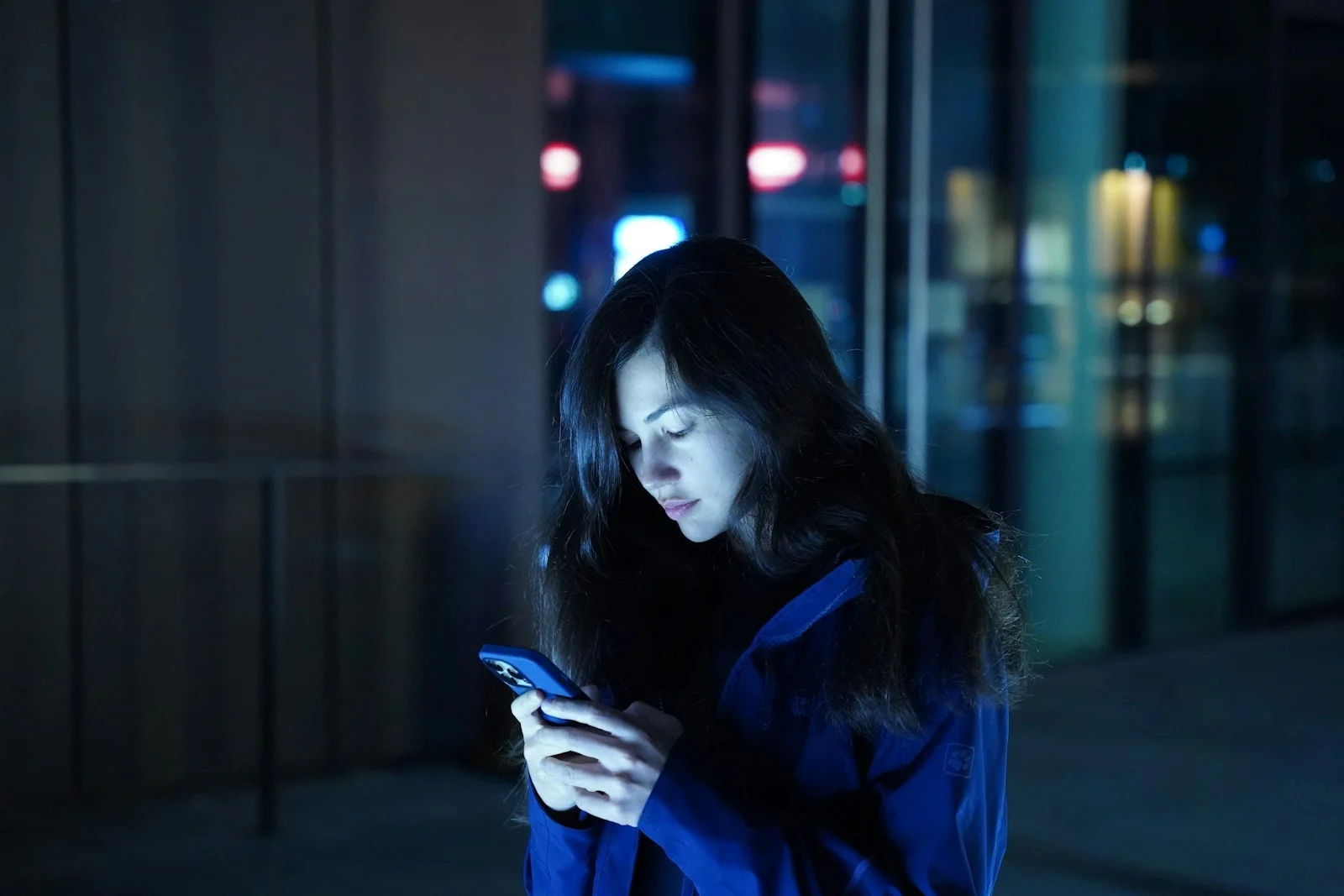Jeune femme qui regarde son téléphone, seule dans le noir