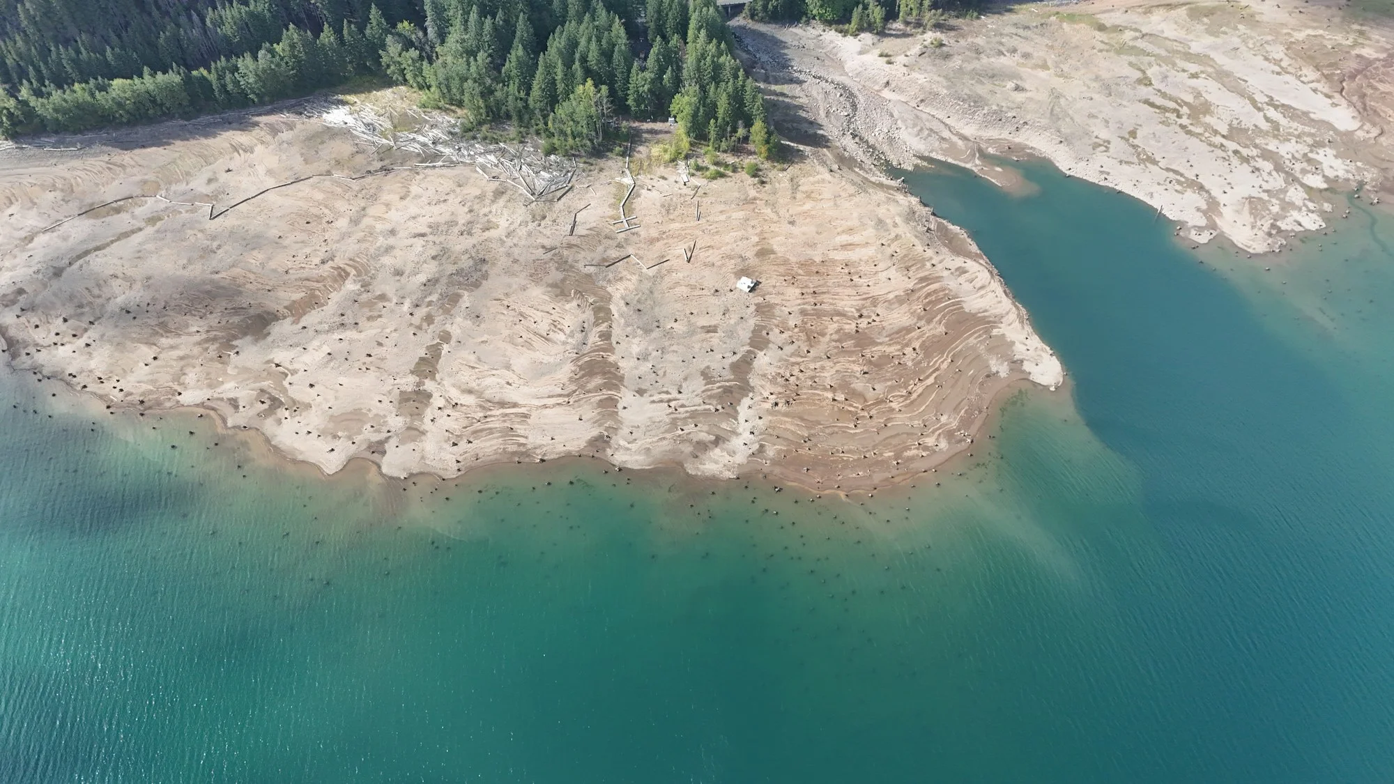 Lac asséché au bord d’une forêt, vu du ciel
